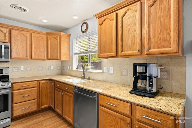 2023 E Wrightwood Dr, Meridian, ID 83642 - kitchen with stainless steel appliances, a sink, light wood-type flooring, light stone countertops, and decorative backsplash