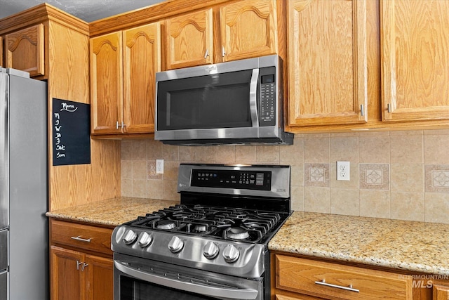 2023 E Wrightwood Dr, Meridian, ID 83642 - kitchen featuring stainless steel appliances, decorative backsplash, light stone counters, and brown cabinets