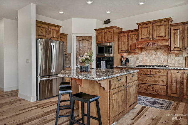 352 N Panorama Pl, Boise, ID 83702 - kitchen with appliances with stainless steel finishes, light wood-type flooring, a center island, dark stone countertops, and recessed lighting