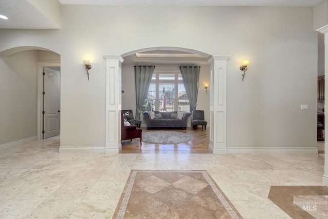 interior space featuring a raised ceiling, crown molding, and baseboards