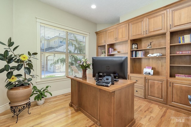 office space with plenty of natural light, light wood-style flooring, baseboards, and a textured ceiling