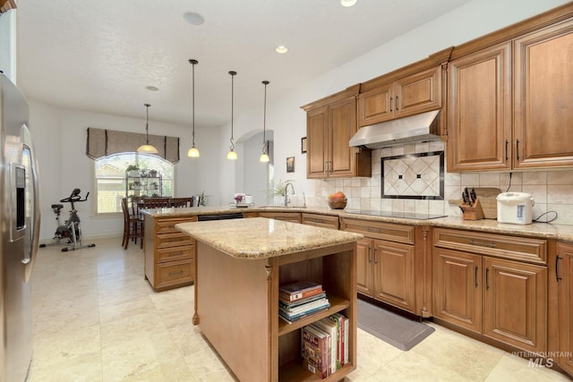 kitchen featuring under cabinet range hood, a peninsula, a sink, brown cabinets, and black appliances