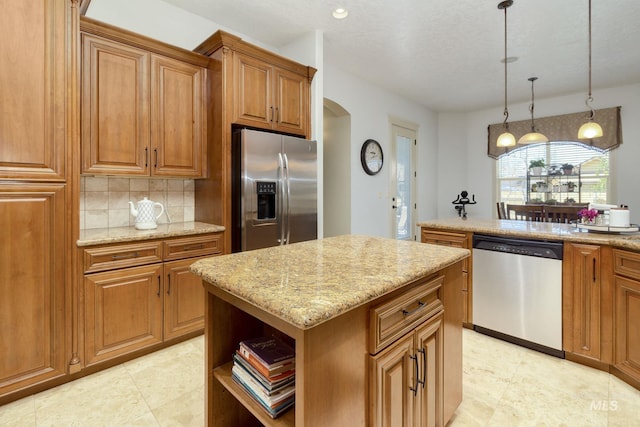 kitchen with brown cabinets, arched walkways, stainless steel appliances, and a center island