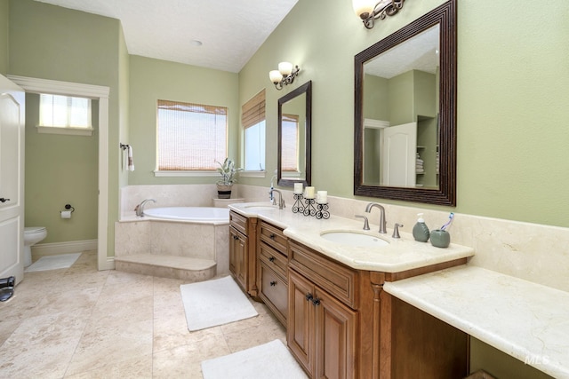 bathroom featuring toilet, a garden tub, double vanity, and a sink