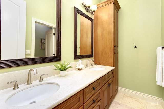 bathroom with double vanity, tile patterned flooring, baseboards, and a sink