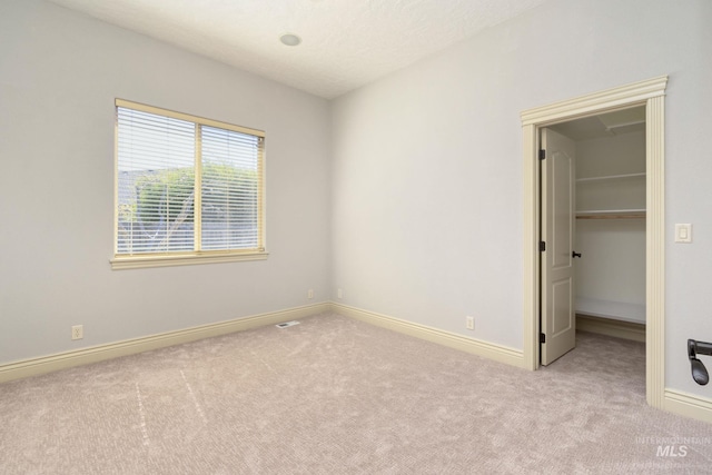 unfurnished bedroom with carpet, baseboards, and a walk in closet