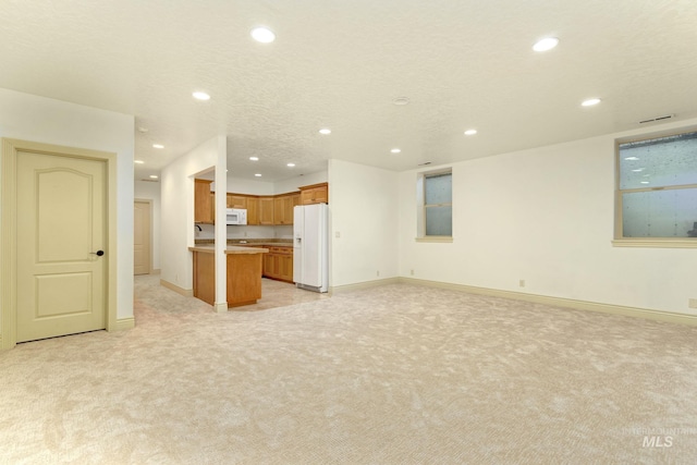 unfurnished living room with a textured ceiling, light colored carpet, recessed lighting, visible vents, and baseboards