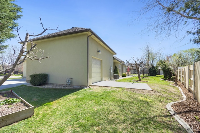 view of property exterior with a garage, a vegetable garden, fence, a yard, and stucco siding