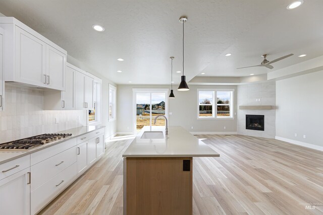 2330 E Monhegan Dr, Eagle, ID 83616 - kitchen featuring a sink, stainless steel gas cooktop, baseboards, decorative backsplash, and light wood-style flooring