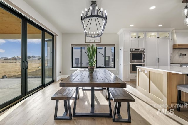 dining space with an inviting chandelier and light hardwood / wood-style flooring