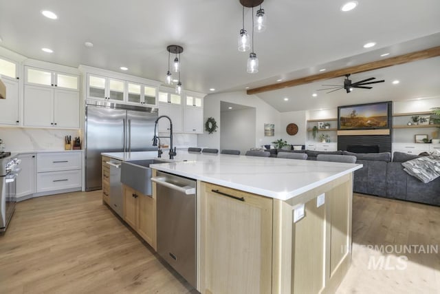 kitchen featuring hanging light fixtures, a large island, white cabinets, light wood-type flooring, and stainless steel appliances