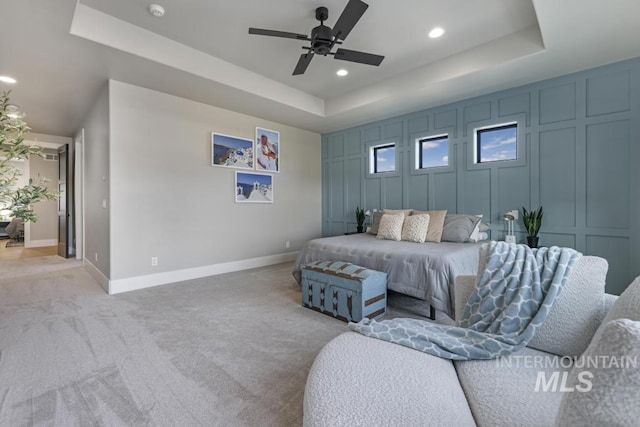 carpeted bedroom featuring ceiling fan and a raised ceiling