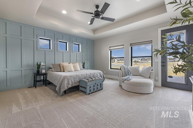 carpeted bedroom featuring ceiling fan and a tray ceiling