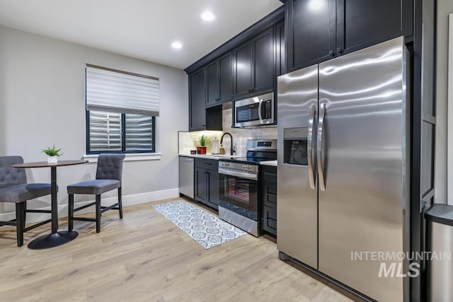 kitchen with sink, stainless steel appliances, light hardwood / wood-style flooring, and decorative backsplash