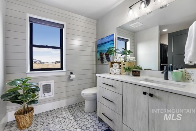 bathroom featuring vanity, toilet, and wooden walls