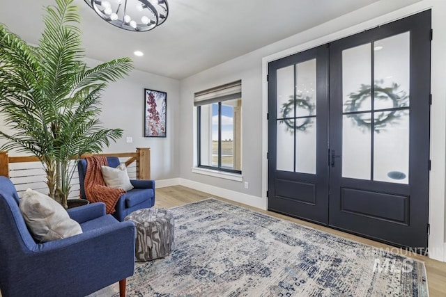 foyer entrance with hardwood / wood-style flooring, a chandelier, and french doors