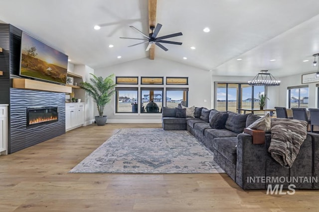 living room with ceiling fan, vaulted ceiling with beams, light hardwood / wood-style flooring, and a fireplace