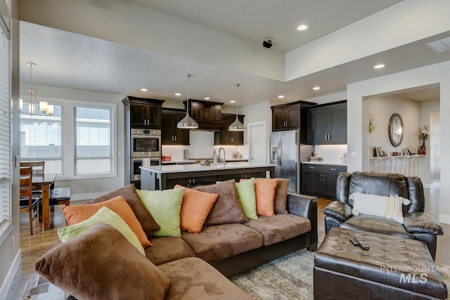 living area featuring an inviting chandelier, light wood-style flooring, baseboards, and recessed lighting