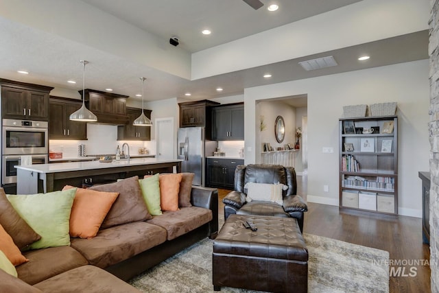 living area featuring baseboards, dark wood-type flooring, visible vents, and recessed lighting