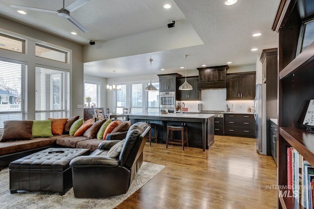 living room featuring light wood-type flooring, a ceiling fan, and recessed lighting