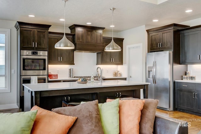 kitchen featuring decorative backsplash, a breakfast bar, stainless steel appliances, dark brown cabinets, and light countertops