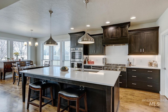 kitchen with a breakfast bar area, appliances with stainless steel finishes, light countertops, and a sink