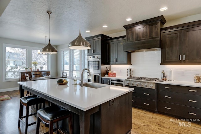 kitchen featuring stainless steel appliances, light countertops, a sink, and decorative backsplash