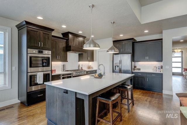 kitchen featuring tasteful backsplash, visible vents, light wood-style flooring, appliances with stainless steel finishes, and a sink