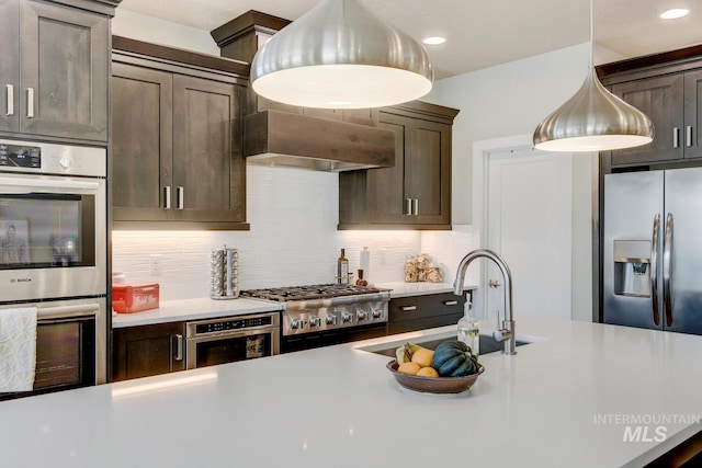 kitchen with extractor fan, stainless steel appliances, a sink, dark brown cabinets, and tasteful backsplash