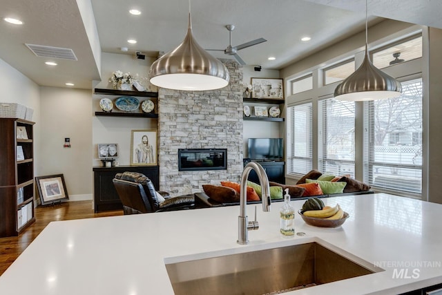 kitchen featuring dark wood-style flooring, a fireplace, a sink, visible vents, and light countertops