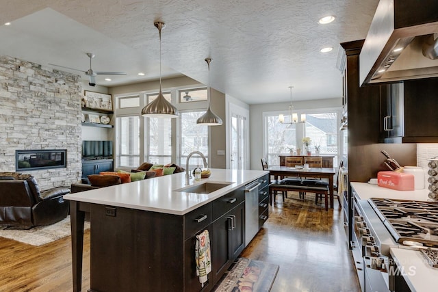 kitchen with wall chimney range hood, light countertops, a sink, and wood finished floors