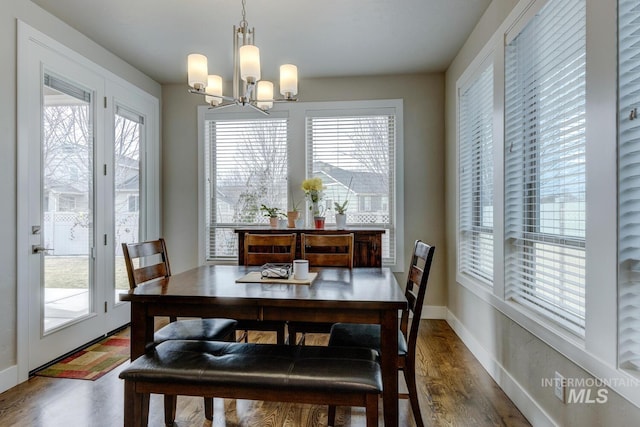 dining space with baseboards, wood finished floors, and an inviting chandelier