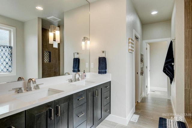 bathroom featuring double vanity, baseboards, visible vents, and a sink