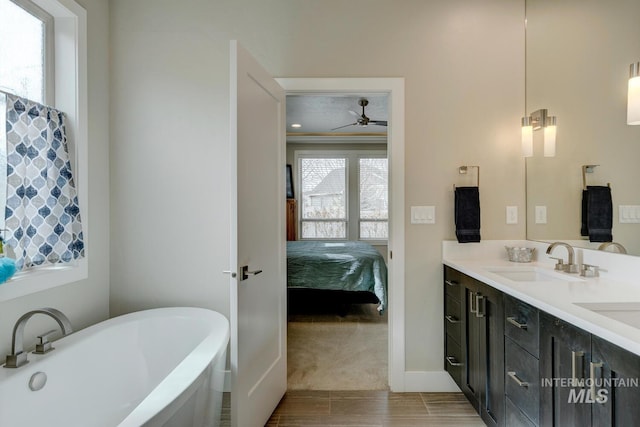 full bathroom featuring ceiling fan, connected bathroom, a sink, a freestanding bath, and double vanity