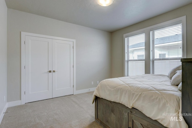 bedroom with light carpet, a closet, and baseboards