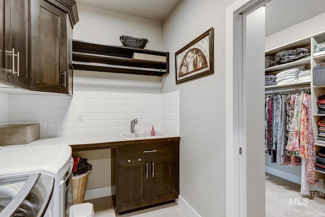 laundry room featuring washer and clothes dryer, a sink, cabinet space, and baseboards