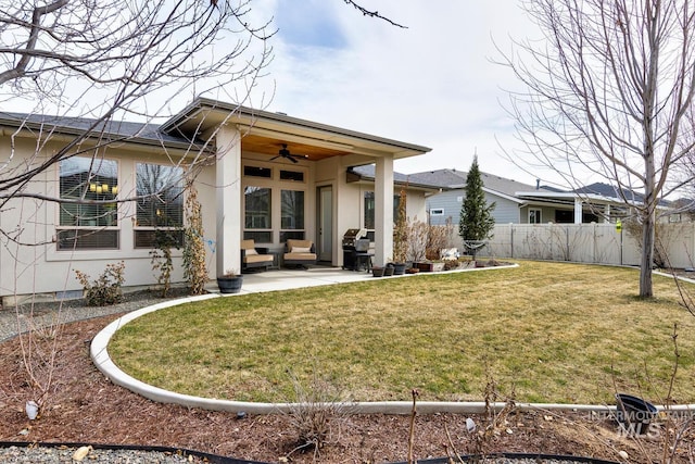 rear view of property featuring a patio, stucco siding, a lawn, a ceiling fan, and fence