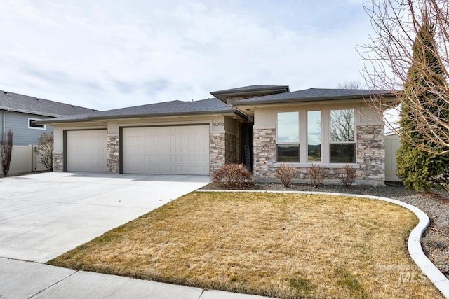 prairie-style house with an attached garage, stone siding, a front lawn, and concrete driveway