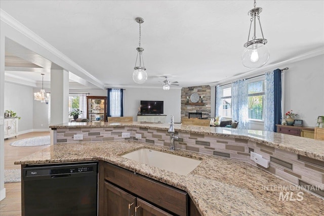 kitchen with a sink, dishwasher, a stone fireplace, ceiling fan with notable chandelier, and open floor plan