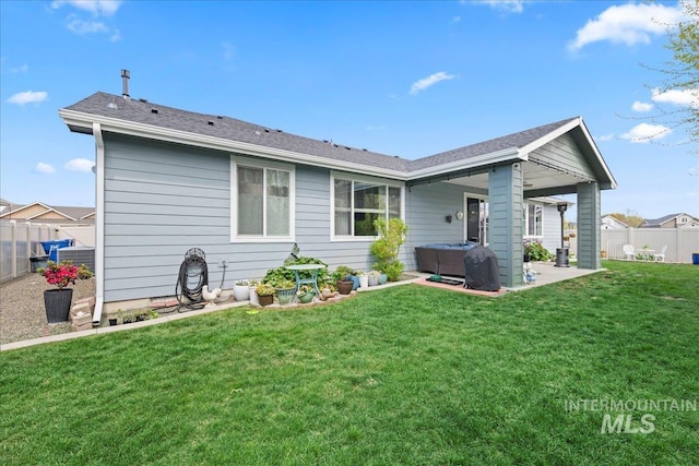 rear view of house with a lawn, a patio, and fence