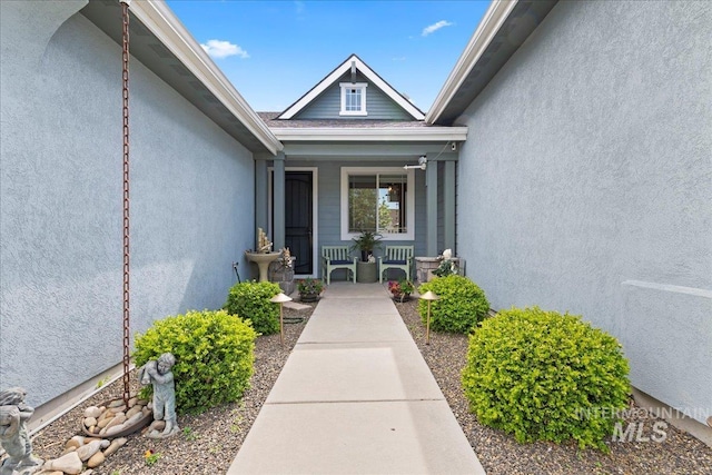 property entrance with a porch and stucco siding