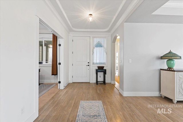 entrance foyer featuring arched walkways, baseboards, a wealth of natural light, and wood finished floors