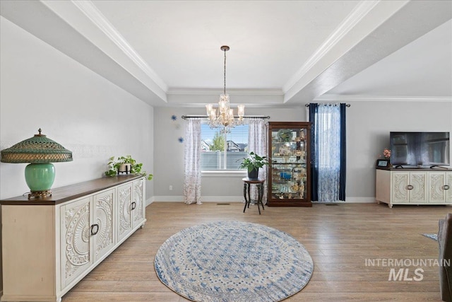 dining room featuring an inviting chandelier, baseboards, wood finished floors, and a tray ceiling