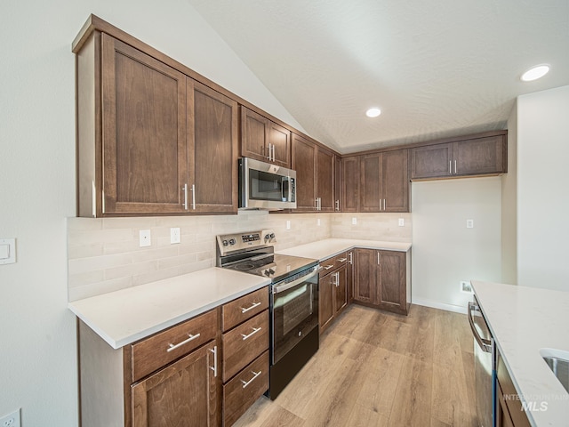 2314 E Cave Falls St, Kuna, ID 83634 - kitchen featuring stainless steel appliances, light wood-type flooring, tasteful backsplash, light countertops, and lofted ceiling