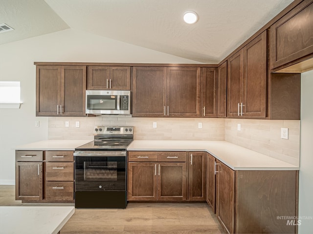 2314 E Cave Falls St, Kuna, ID 83634 - kitchen featuring appliances with stainless steel finishes, vaulted ceiling, light countertops, backsplash, and light wood-type flooring