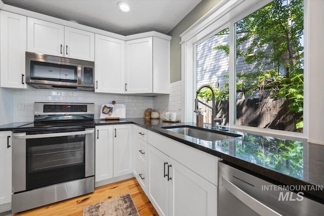 1803 E Danmor Dr, Boise, ID 83712 - kitchen featuring appliances with stainless steel finishes, a sink, tasteful backsplash, white cabinets, and light wood finished floors