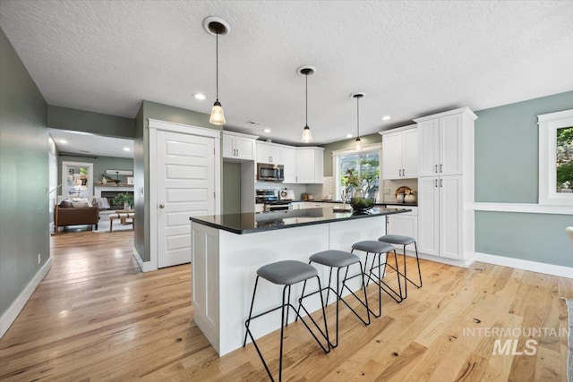 1803 E Danmor Dr, Boise, ID 83712 - kitchen with appliances with stainless steel finishes, white cabinets, dark countertops, light wood-style floors, and a textured ceiling