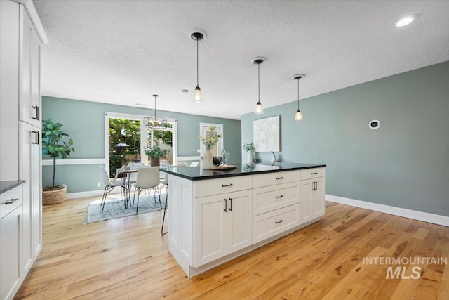 1803 E Danmor Dr, Boise, ID 83712 - kitchen with dark countertops, light wood-type flooring, white cabinets, a textured ceiling, and recessed lighting