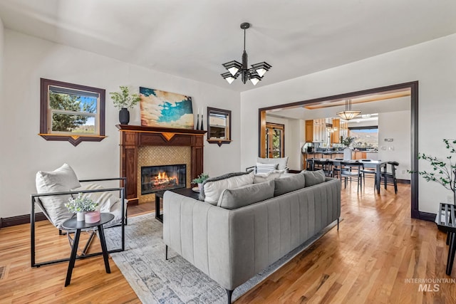4997 N Brookside Ln, Boise, ID 83714 - living room with a chandelier, a glass covered fireplace, light wood-style flooring, and baseboards