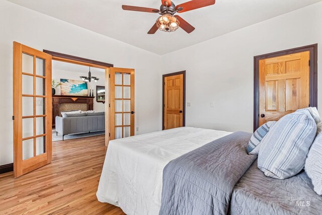 4997 N Brookside Ln, Boise, ID 83714 - bedroom featuring light wood-style floors, french doors, a chandelier, and a ceiling fan